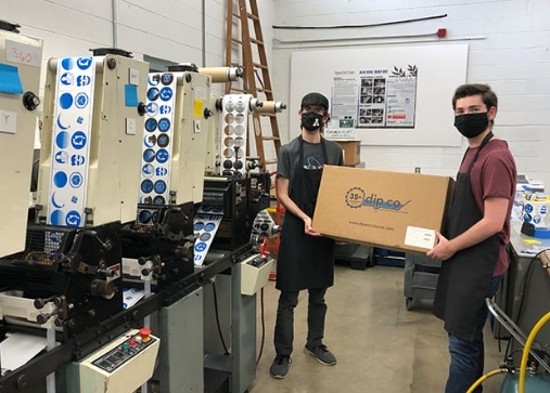 2 Dipco factory works holding a box that is getting prepared for shipping